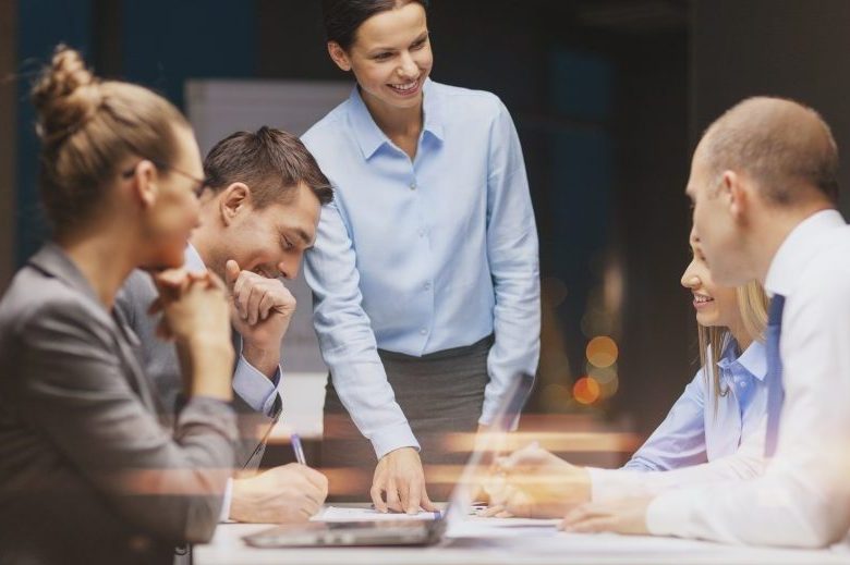 business, technology and office concept - smiling female boss talking to business team